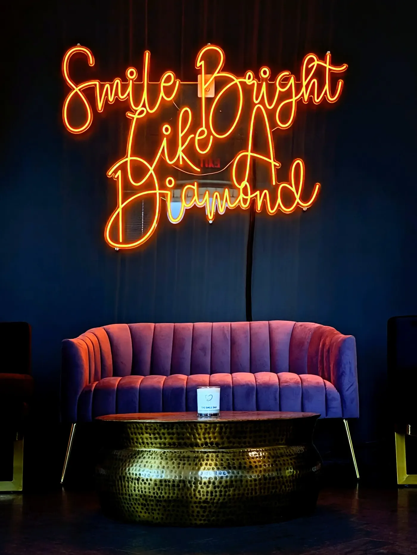 The Smile Bar lounge — Smile Bright Like A Diamond neon sign above a velvet sofa