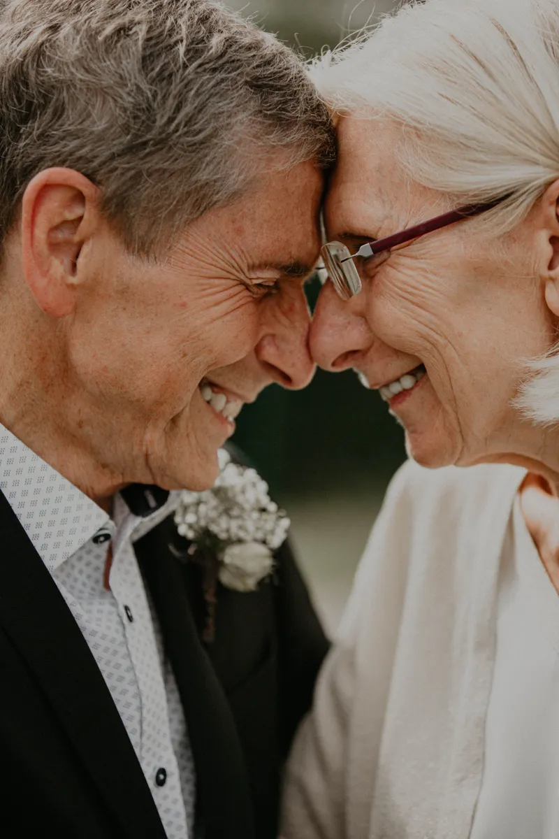 Senior couple smiling forehead to forehead — life after dental implants
