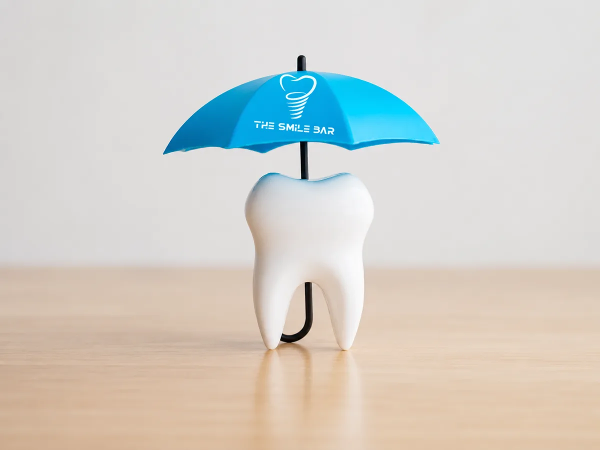 A tooth model sheltered under a small umbrella — coverage that protects your dental care