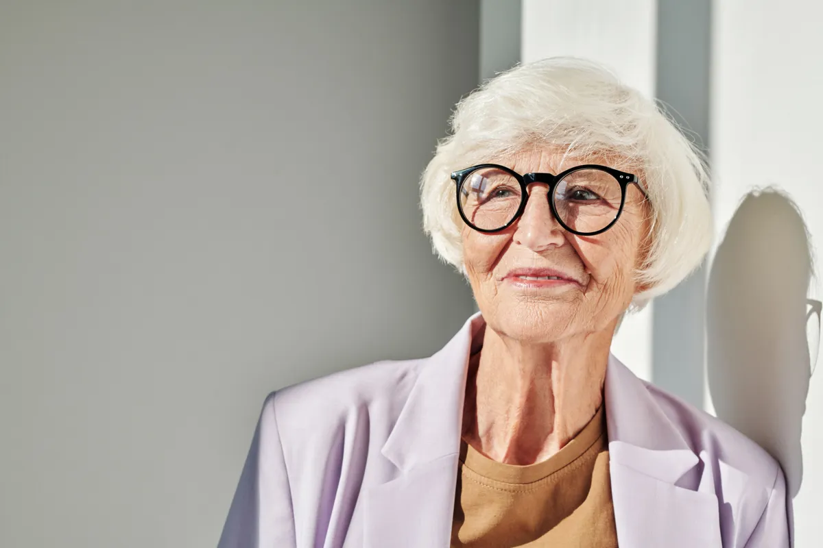 Elegant older woman smiling with confidence — implant-supported dentures