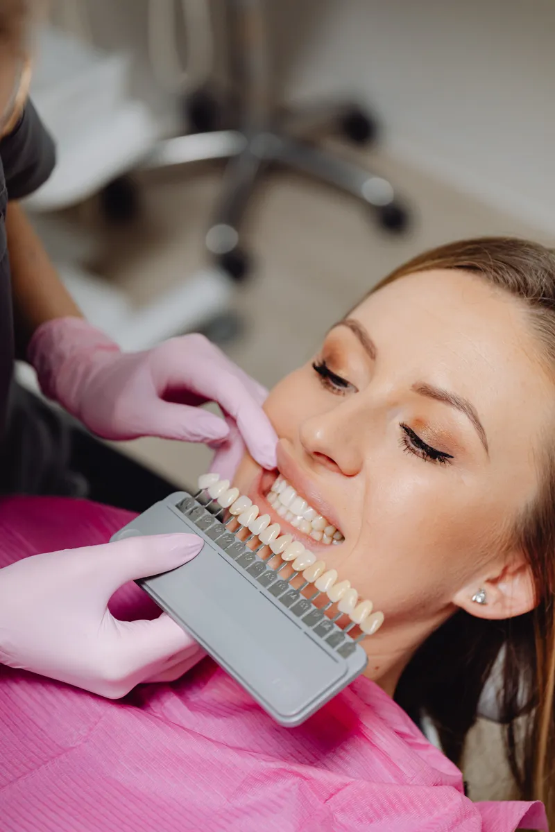 Dentist matching porcelain veneer shades against a patient's smile