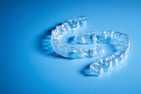 A pair of clear aligners against a blue background